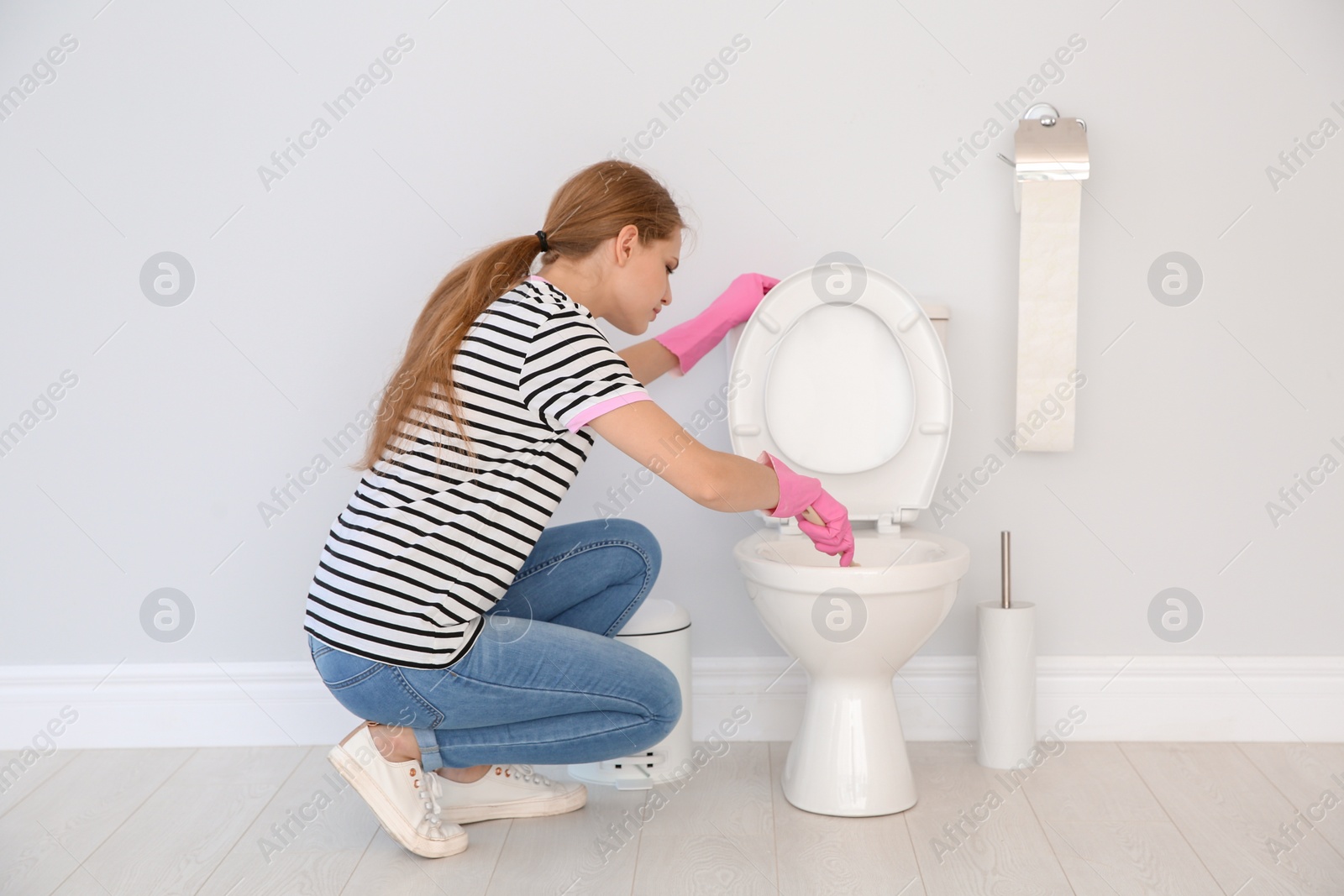 Photo of Woman cleaning toilet bowl in bathroom