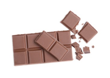 Pieces of delicious milk chocolate bar on white background, top view