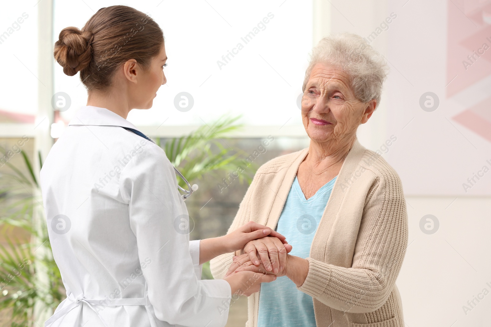 Photo of Nurse comforting elderly woman indoors. Assisting senior generation