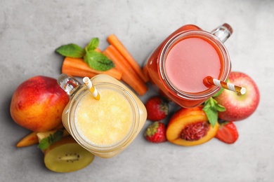 Delicious juices and fresh ingredients on grey table, flat lay