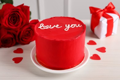 Photo of Bento cake with text Love You, roses, paper hearts and gift box on white wooden table. St. Valentine's day surprise