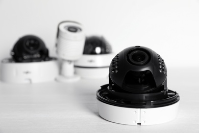 Photo of Modern CCTV cameras on table against light background. Home alarm system