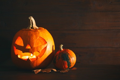 Photo of Halloween pumpkin head jack lantern on table against wooden background with space for text