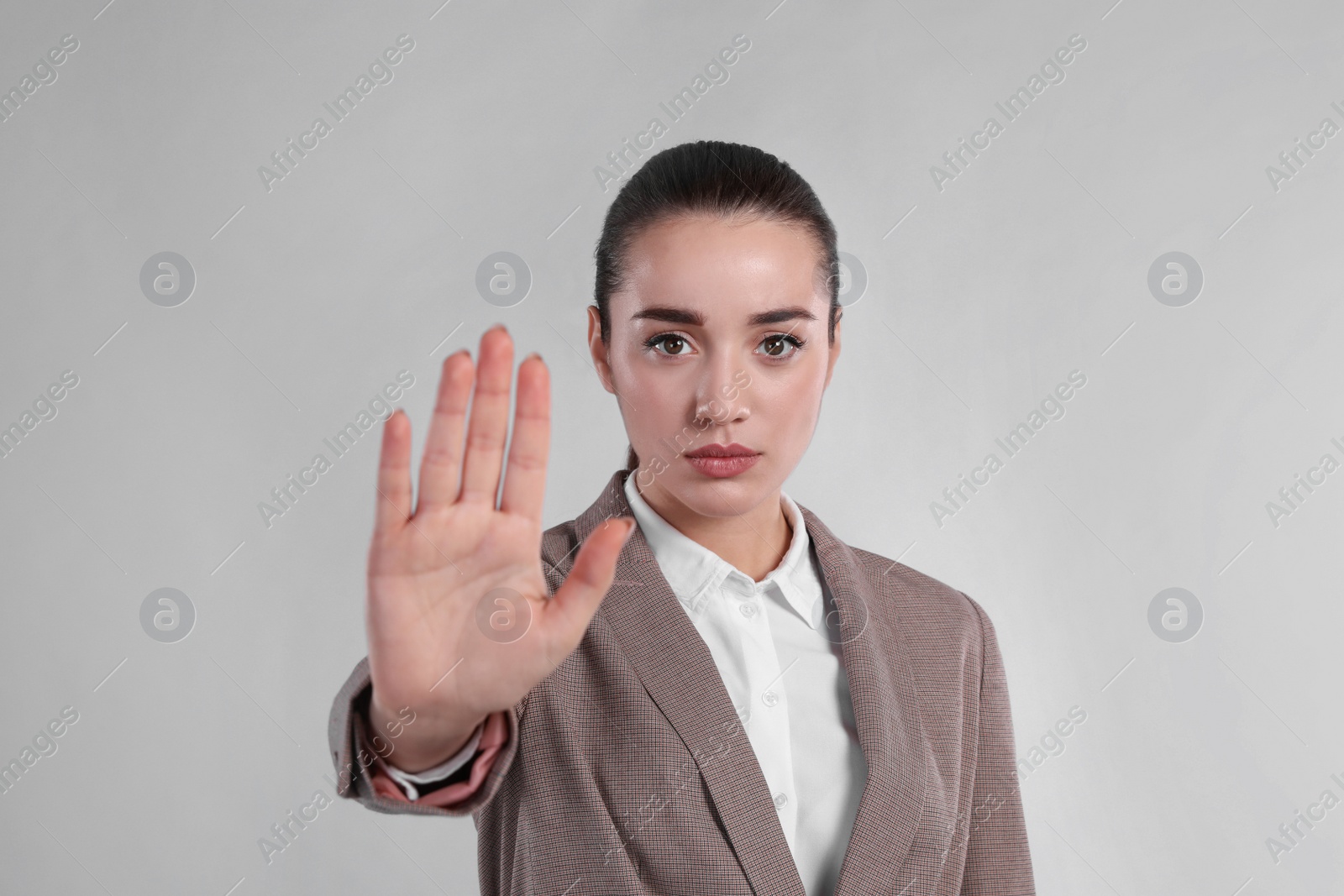 Photo of Woman in suit showing gesture stop on light grey background