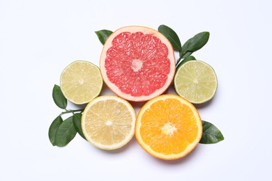 Different cut citrus fruits and leaves on white table, flat lay