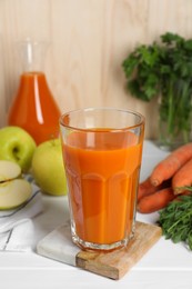 Photo of Tasty carrot juice and ingredients on white wooden table