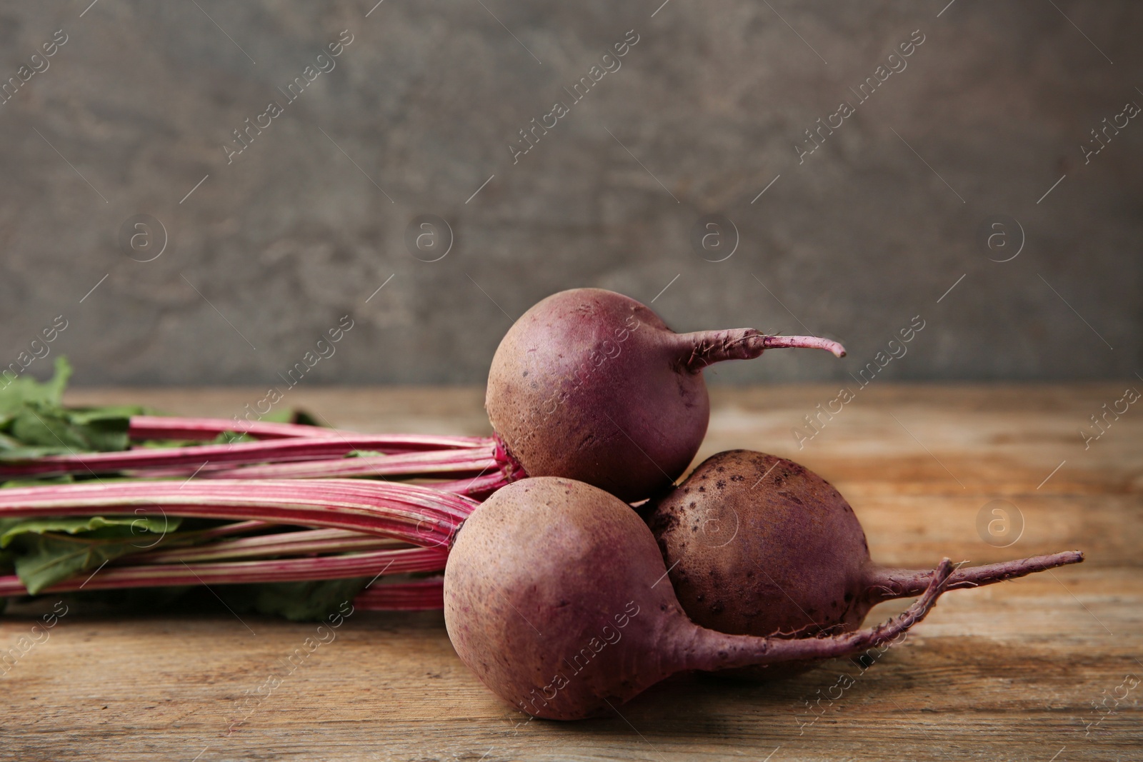 Photo of Bunch of fresh beets on wooden table against grey background. Space for text