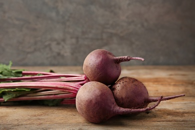 Bunch of fresh beets on wooden table against grey background. Space for text