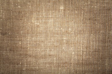 Texture of natural burlap fabric as background, top view. Vignette effect 