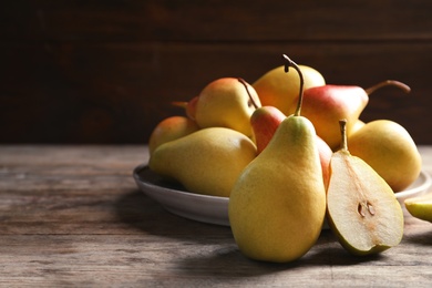 Ripe pears on wooden table against dark background. Space for text