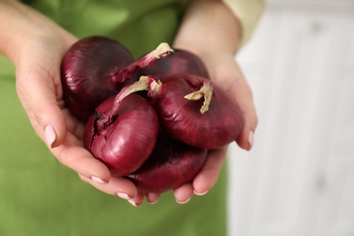 Woman holding red onions on blurred background, closeup