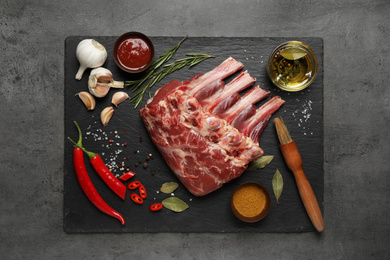 Photo of Raw ribs with herbs and spices on grey table, flat lay