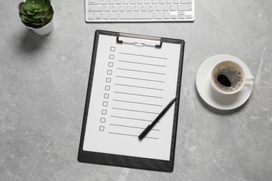 Photo of Clipboard with checkboxes, cup of coffee plant and computer keyboard on light grey table, flat lay. Checklist
