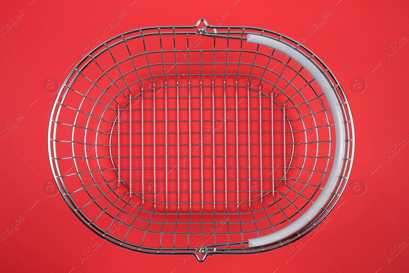 Photo of Empty metal shopping basket on red background, top view