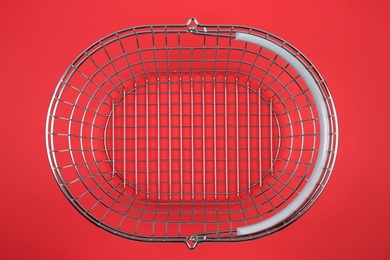 Empty metal shopping basket on red background, top view