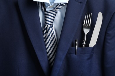 Photo of Cutlery and pen in breast pocket of men`s jacket as background, closeup. Business lunch concept