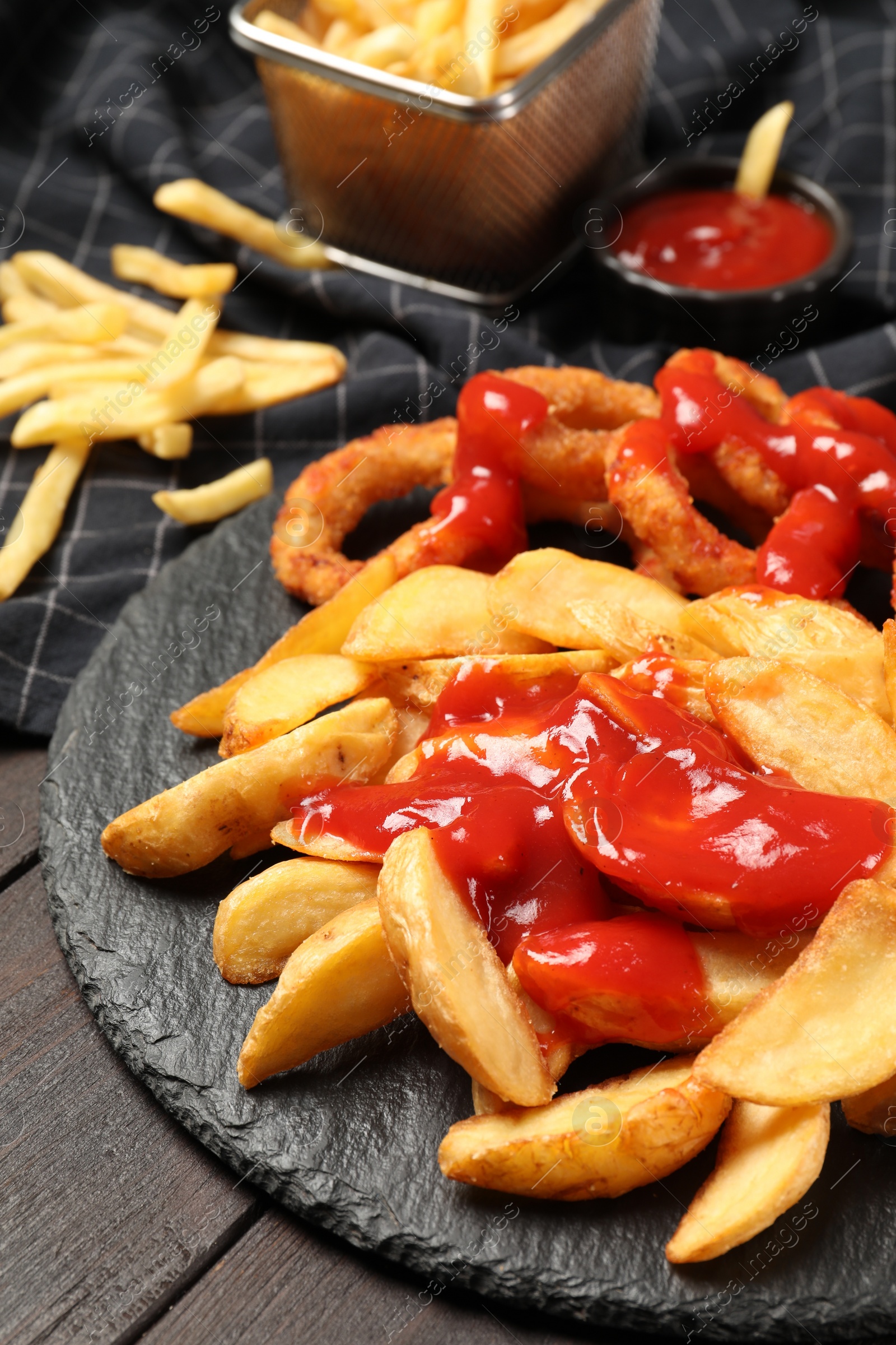 Photo of Delicious baked potato and onion rings with ketchup on table, closeup