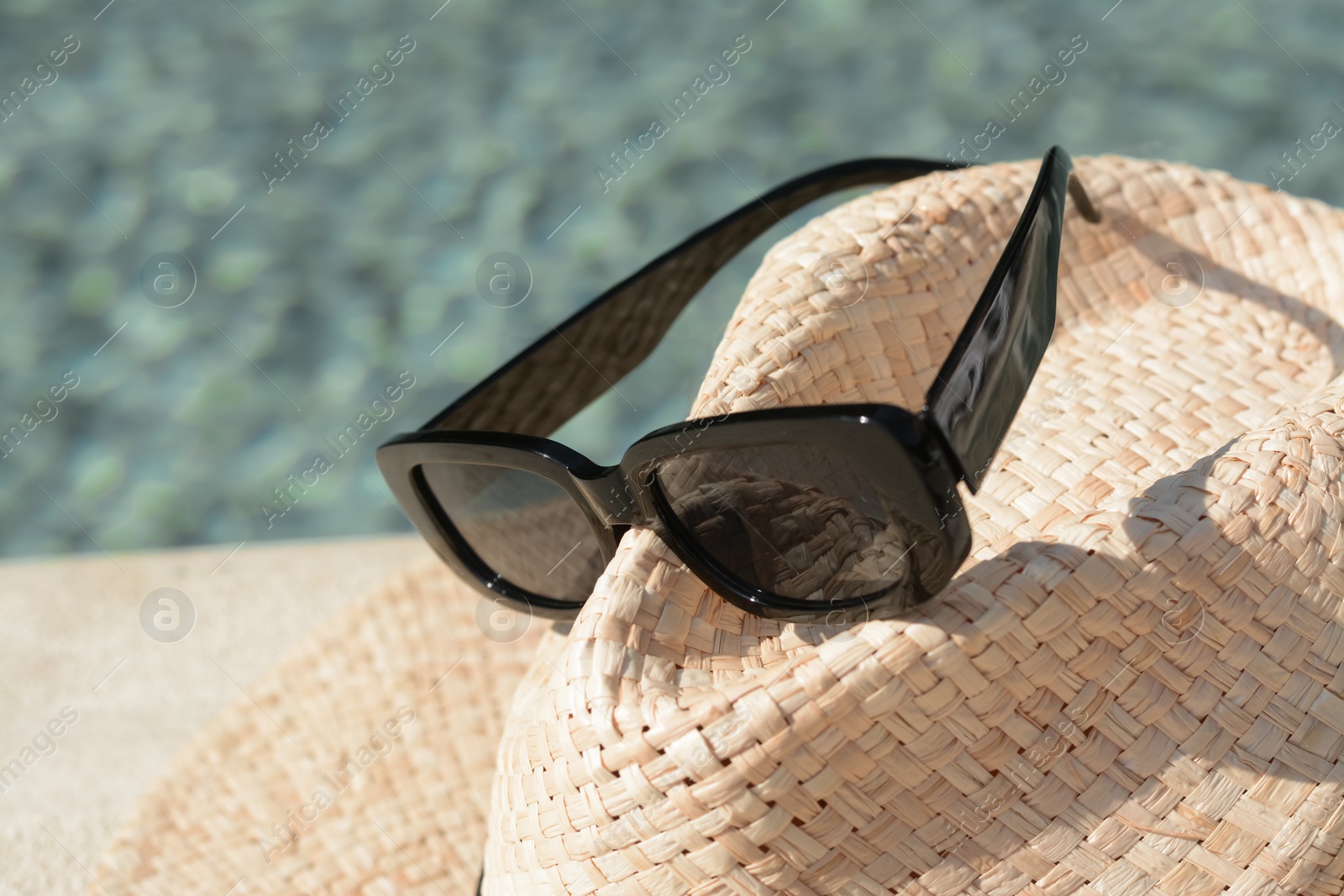 Photo of Stylish hat and sunglasses on blurred background, closeup