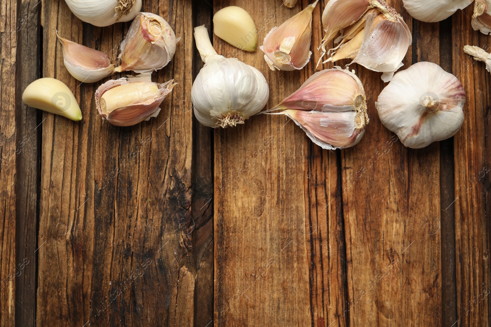 Photo of Fresh organic garlic on wooden table, flat lay. Space for text