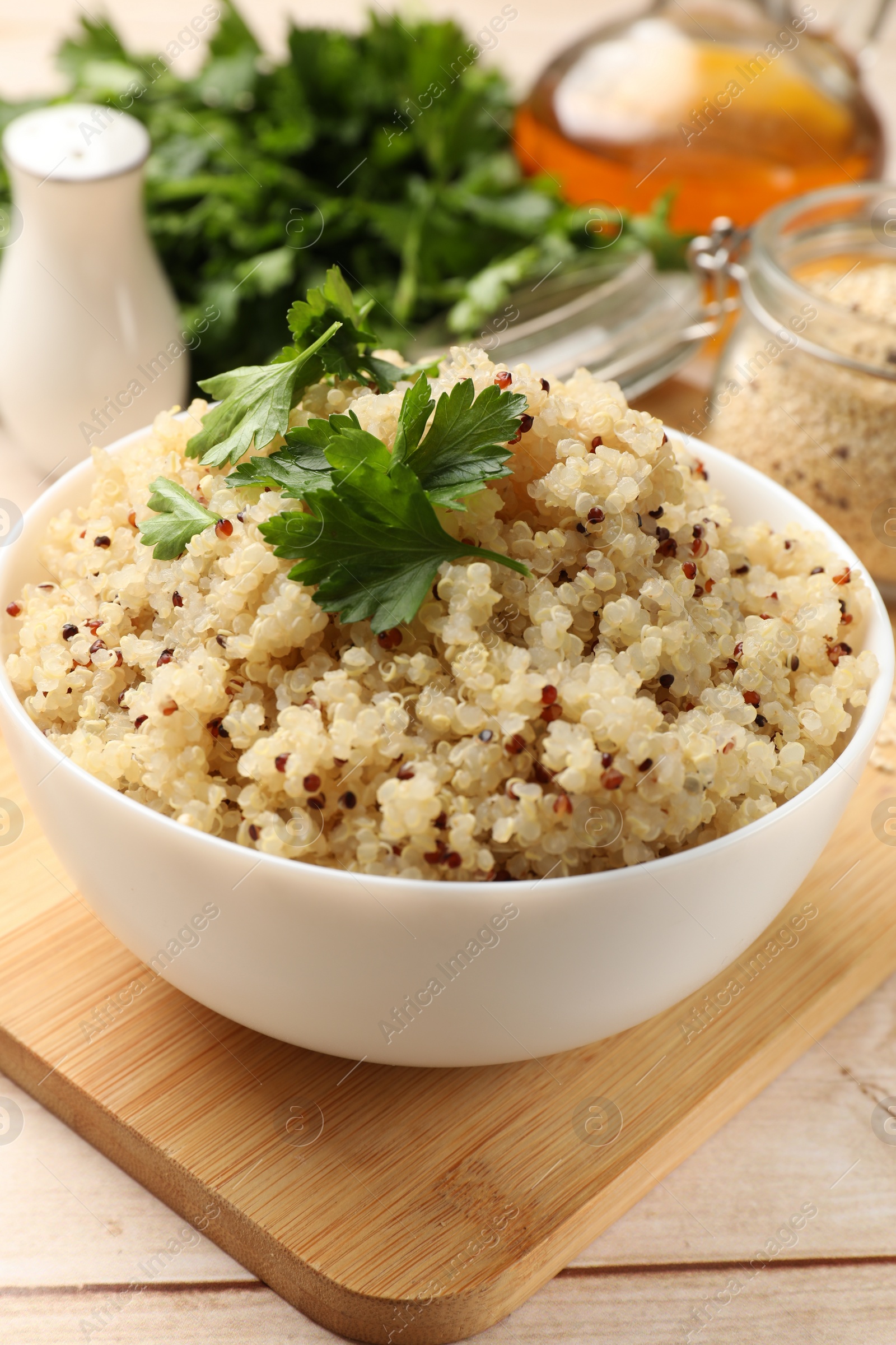 Photo of Tasty quinoa porridge with parsley in bowl on light table, closeup