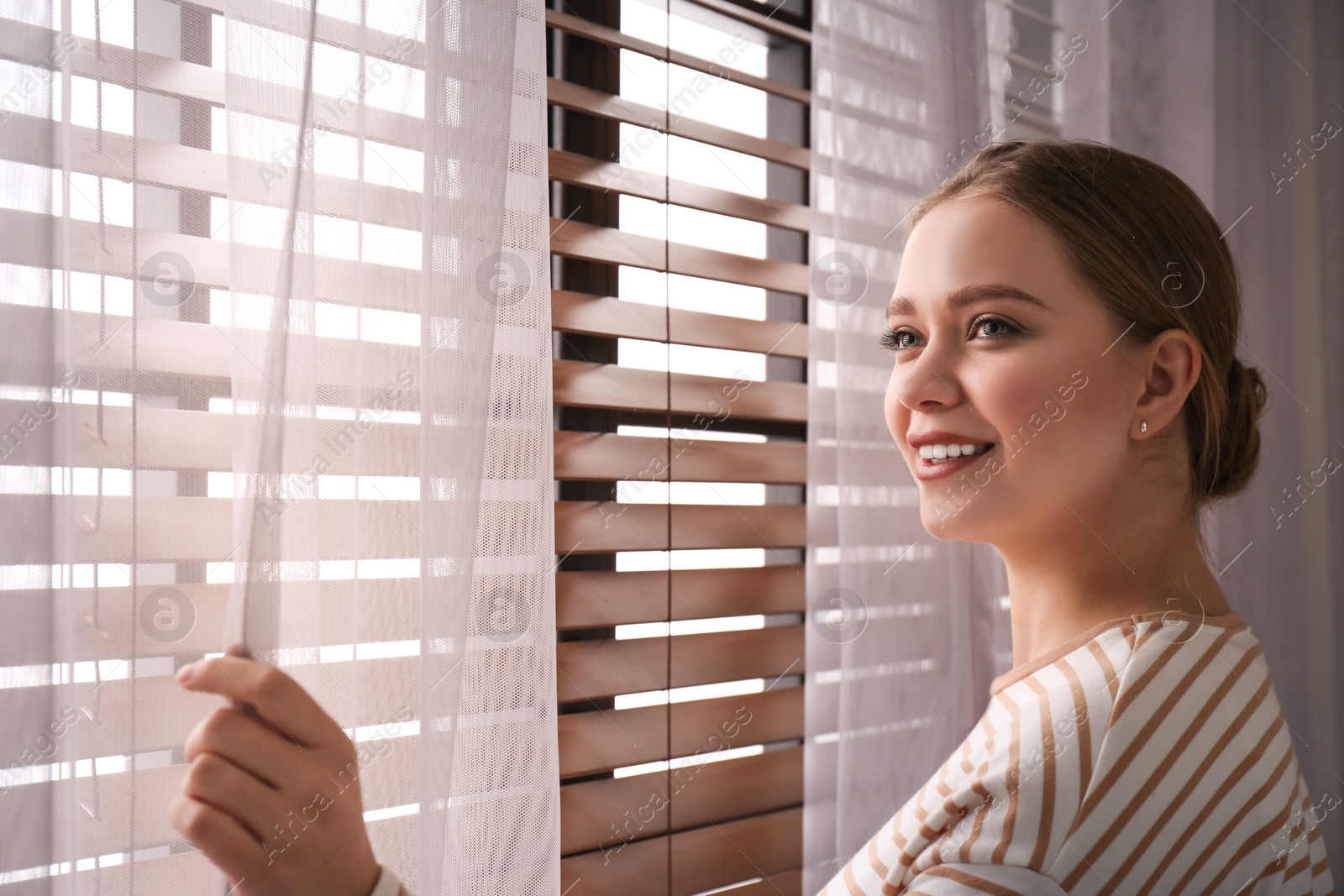 Photo of Woman near window with beautiful curtains at home