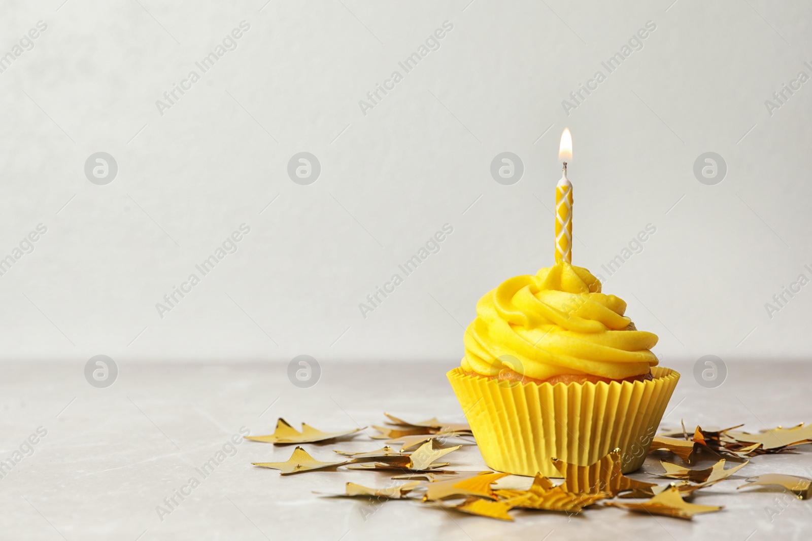 Photo of Delicious birthday cupcake with cream and burning candle on table. Space for text