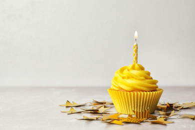 Photo of Delicious birthday cupcake with cream and burning candle on table. Space for text