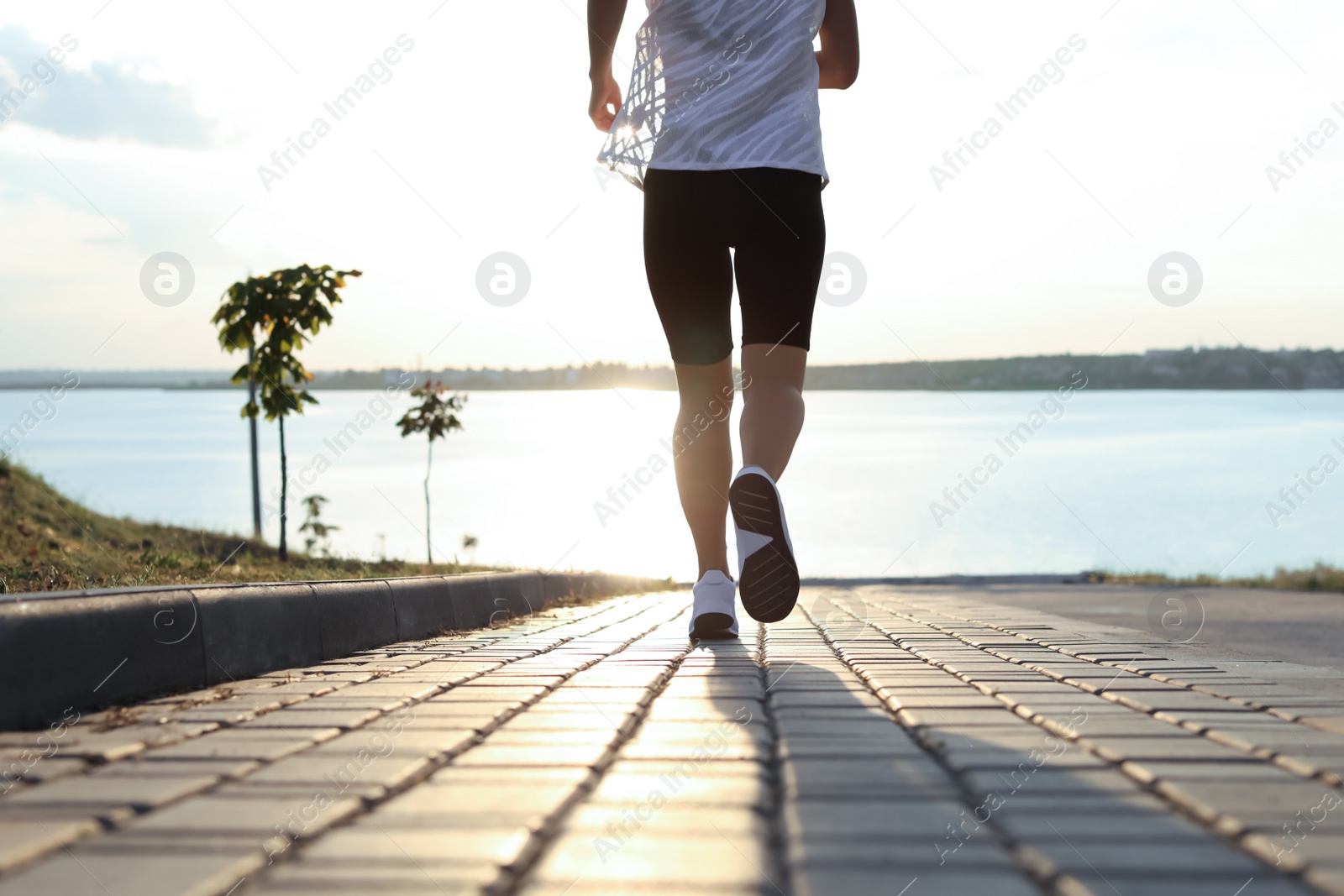 Photo of Young woman running near river in morning, closeup