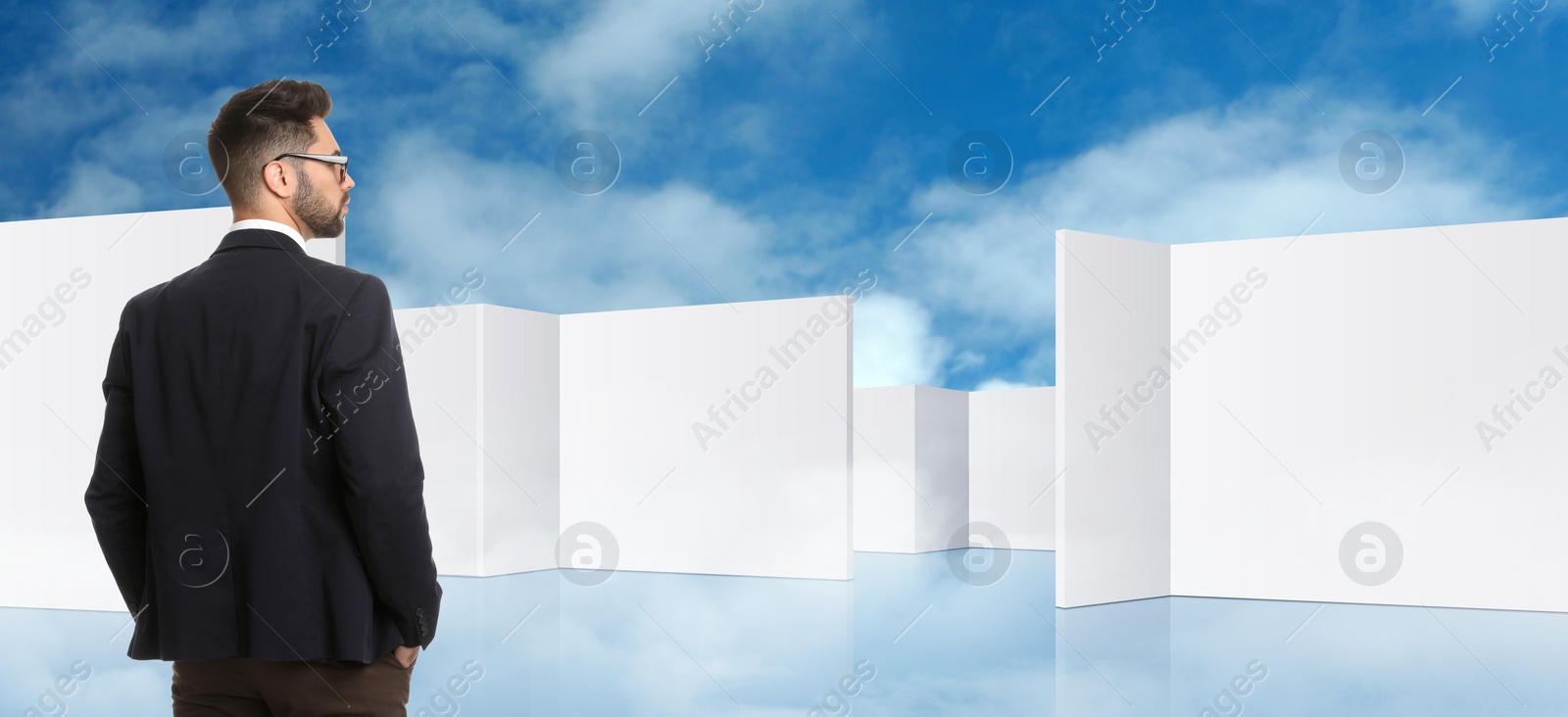 Image of Young businessman in suit looking for way out of maze. Banner design