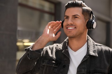 Photo of Handsome man with headphones listening to music on city street