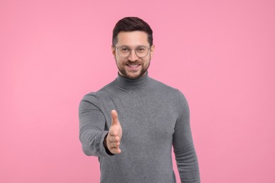 Photo of Happy man welcoming and offering handshake on pink background