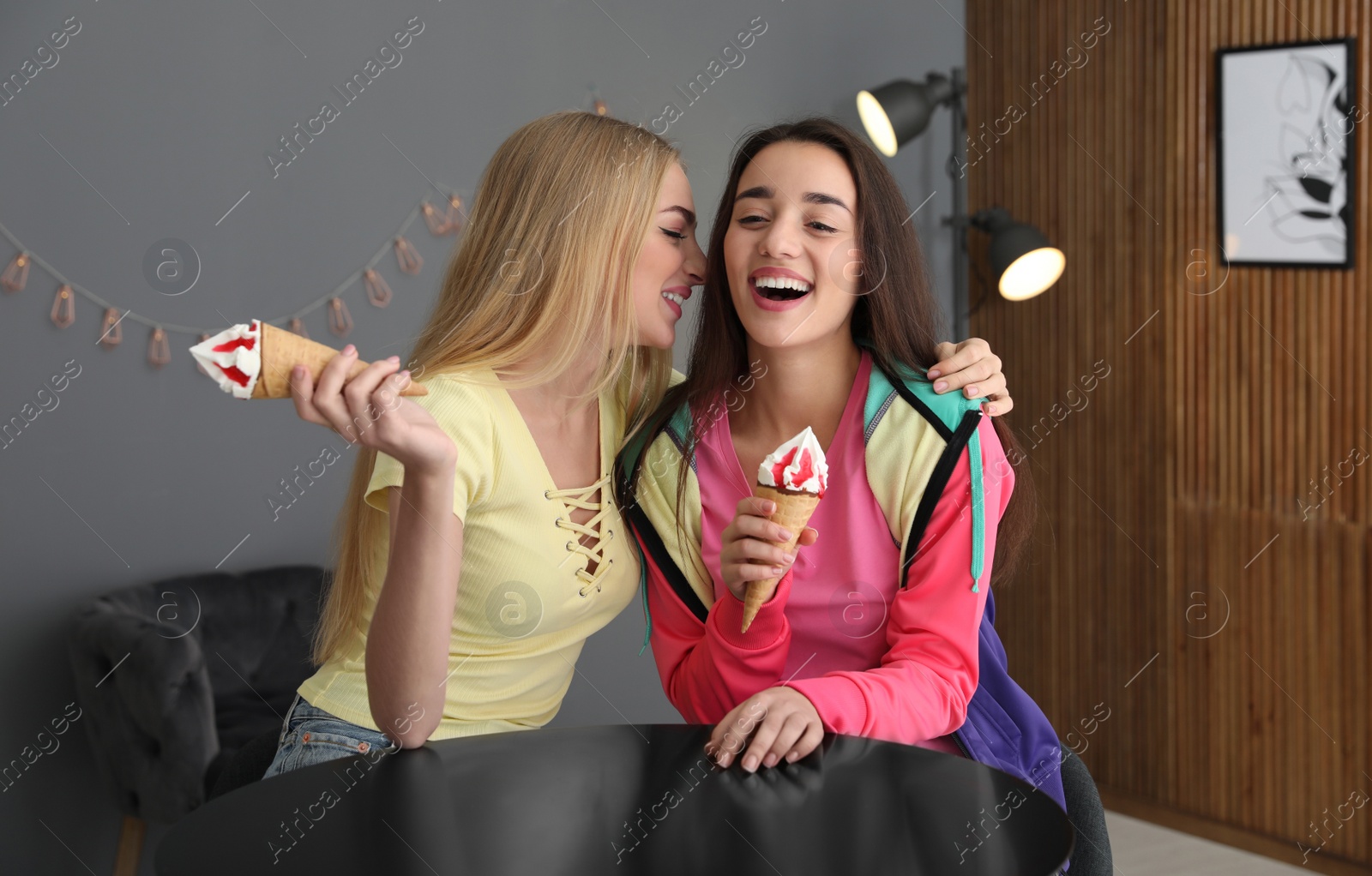 Photo of Young women with ice cream laughing together indoors