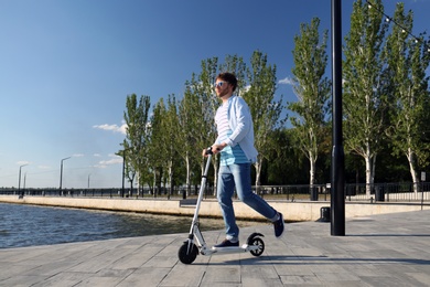 Man riding modern kick scooter along waterfront