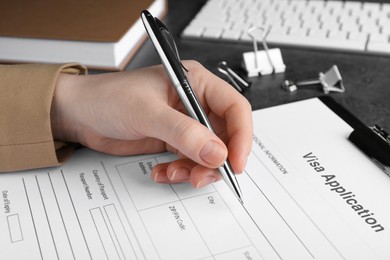 Photo of Woman filling visa application form for immigration at grey table, closeup