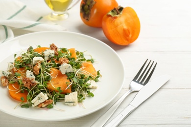 Photo of Delicious persimmon salad served on white wooden table, closeup
