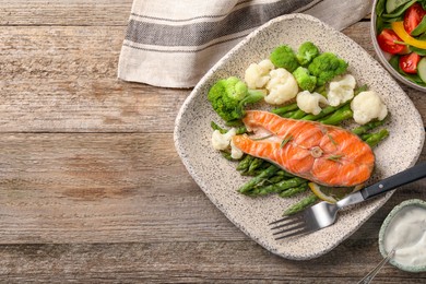 Photo of Healthy meal. Tasty grilled salmon with vegetables served on wooden table, flat lay. Space for text