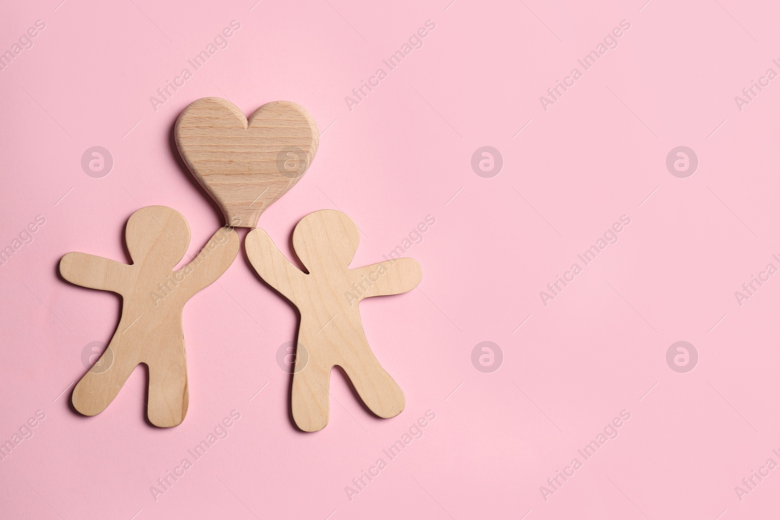 Photo of Wooden figures of couple and heart on pink background, top view with space for text. Happy family