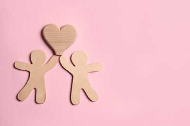 Wooden figures of couple and heart on pink background, top view with space for text. Happy family