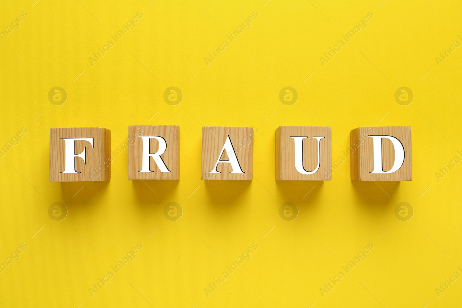 Photo of Wooden cubes with word Fraud on yellow background, flat lay