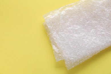 Photo of Transparent bubble wrap on yellow background, top view. Space for text