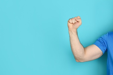 Photo of Young man showing clenched fist on color background. Space for text