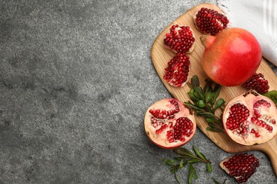 Photo of Delicious ripe pomegranates on grey table, flat lay. Space for text