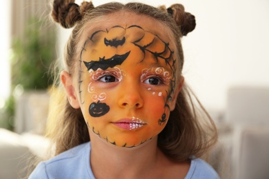 Photo of Cute little girl with face painting indoors