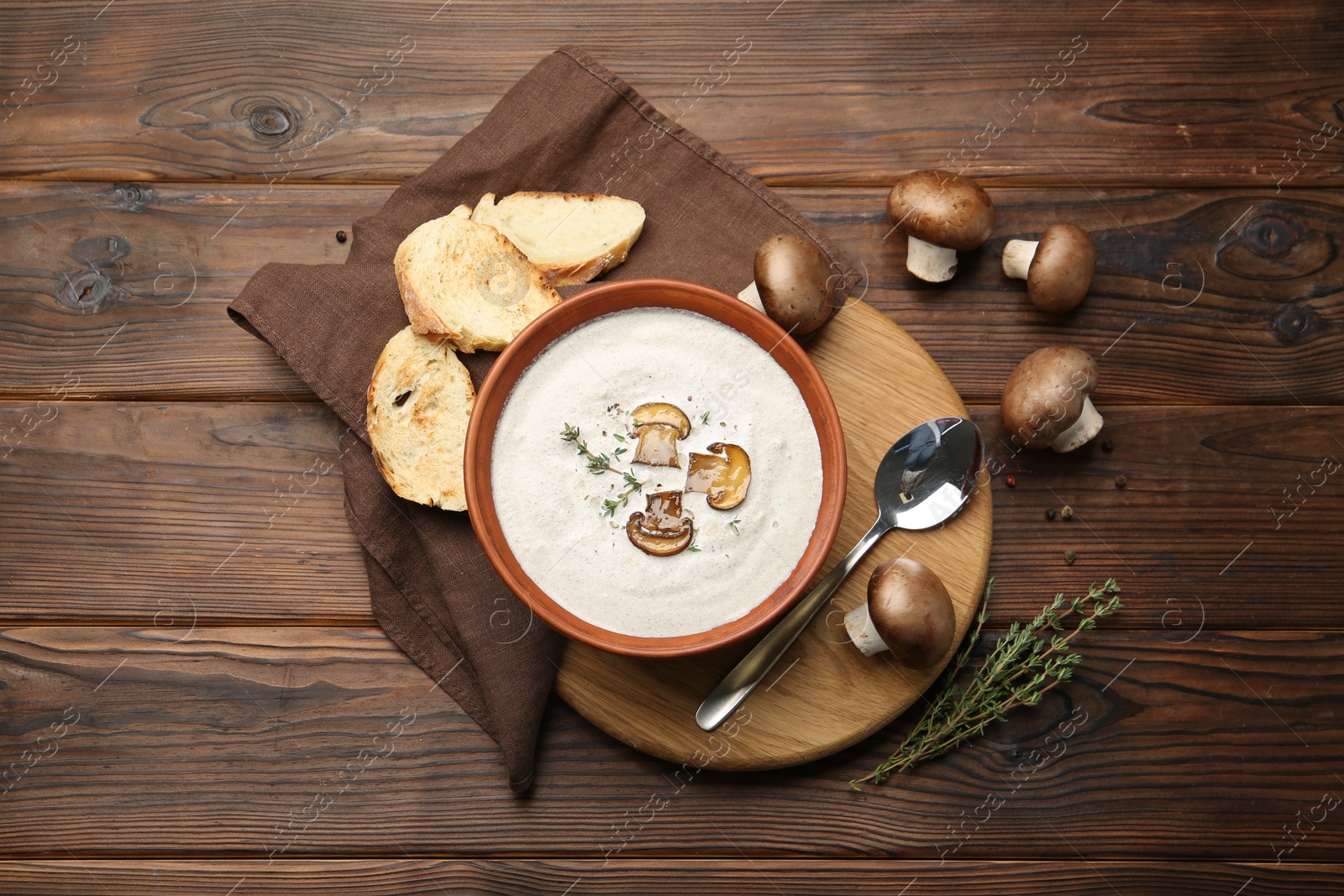 Photo of Fresh homemade mushroom soup served on wooden table, flat lay