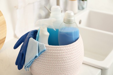Photo of Different cleaning supplies in basket on countertop, closeup