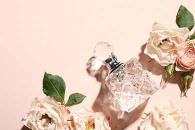 Photo of Bottle of perfume and flowers on beige background, flat lay. Space for text