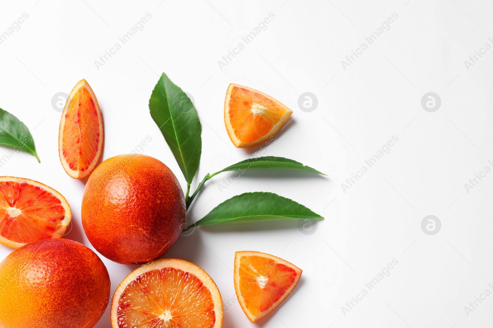 Photo of Fresh bloody oranges and leaves on white background, top view. Citrus fruits