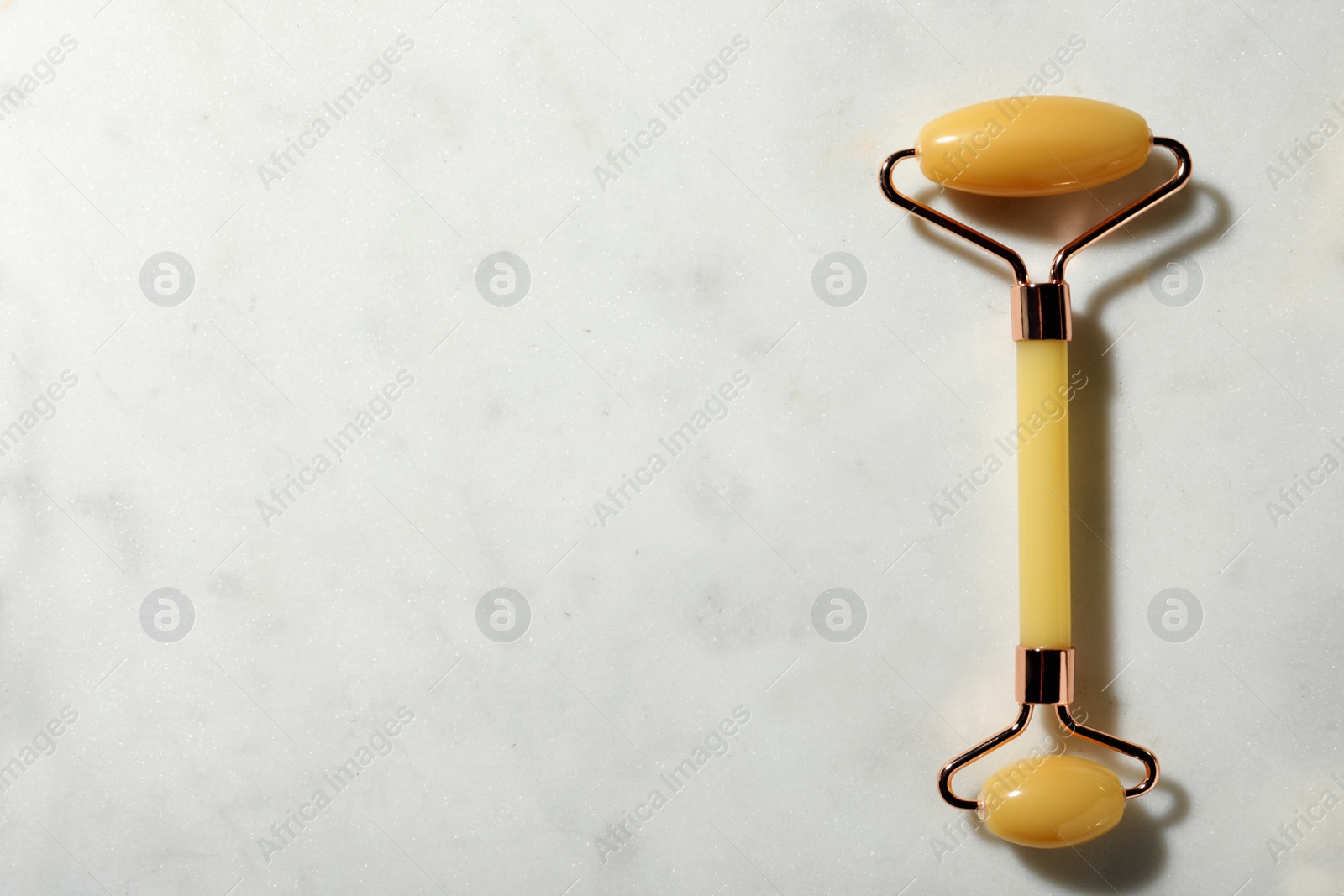 Photo of Natural jade face roller on light background, top view. Space for text