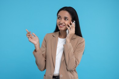 Photo of Beautiful secretary talking on phone against light blue background