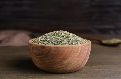 Photo of Bowl of dried dill on wooden table, closeup